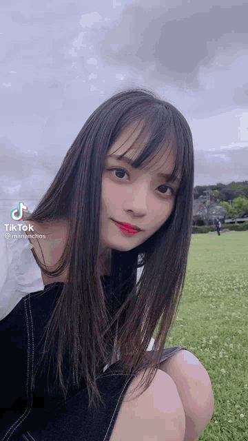 a girl with long black hair is kneeling down in a field .
