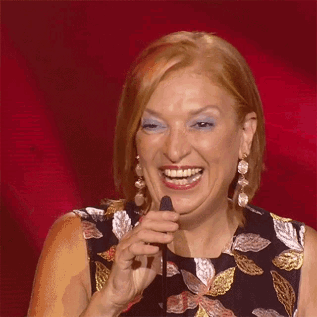 a woman with red hair and blue eye shadow is smiling