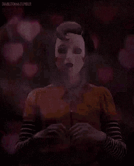 a woman wearing a mask is making a heart shape with her hands .