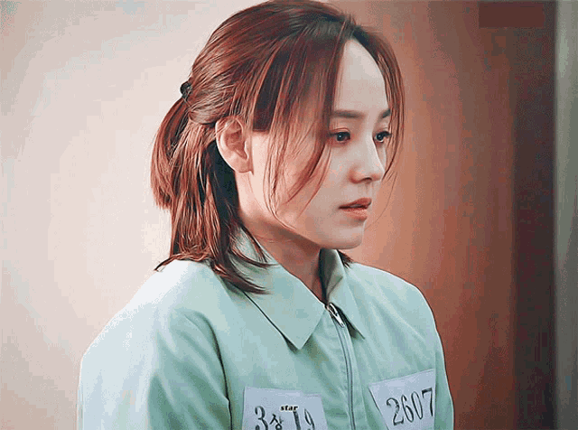 a woman in a prison uniform has a tag that says 2907 on it