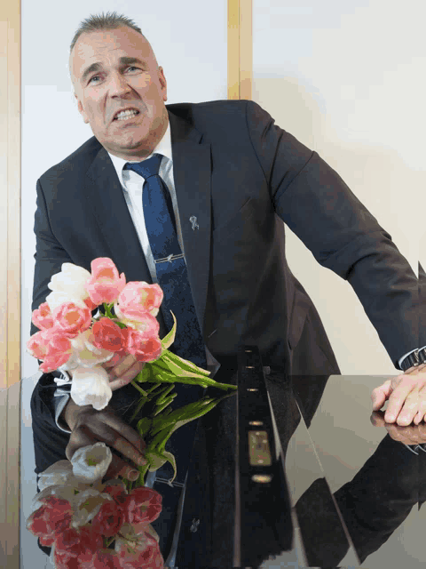 a man in a suit and tie is holding a bouquet of pink and white tulips
