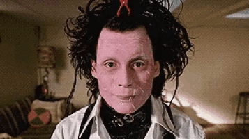 a man with pink paint on his face is standing in a living room looking at the camera .