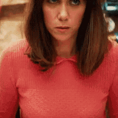 a woman in a red sweater is looking at the camera with a serious look on her face .