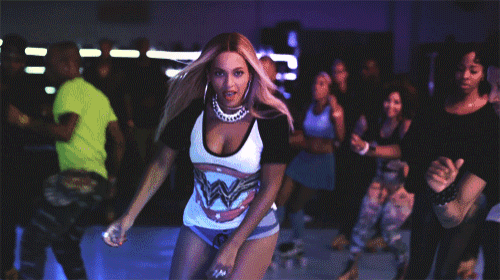 a woman in a rolling stones shirt is dancing in front of a group of people