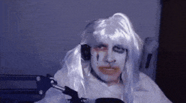 a man is wearing a white wig and headphones while sitting in front of a microphone .