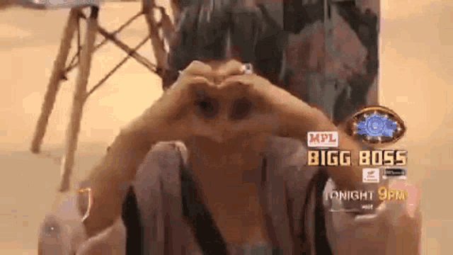 a woman is making a heart shape with her hands in front of her face