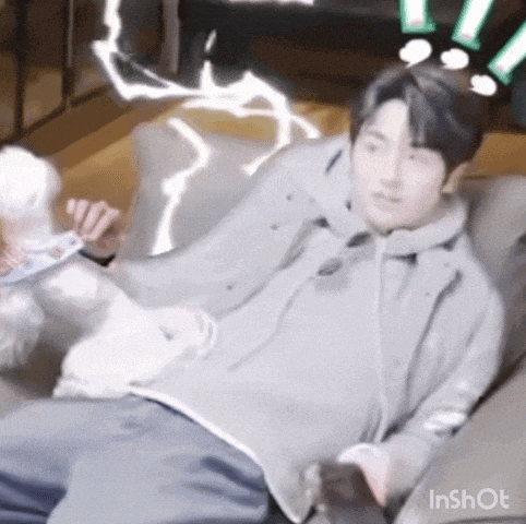 a man is laying on a couch with a white dog behind him .