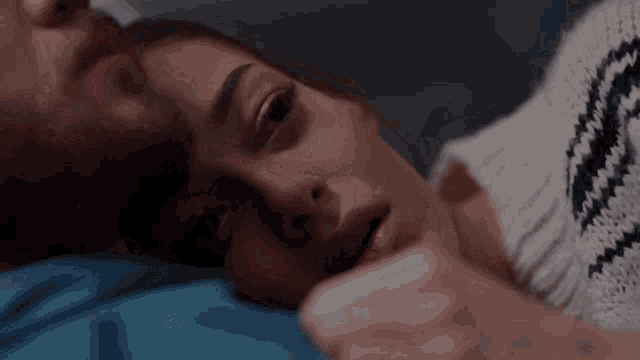 a man and a woman are laying on a bed and the woman is looking at the camera .