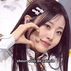 a close up of a girl making a heart shape with her hand