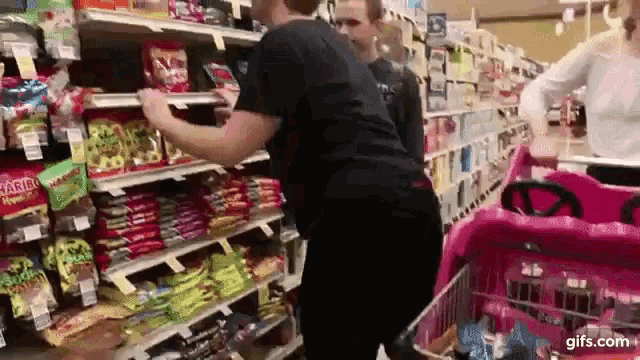 a man is standing in a grocery store looking at candy .