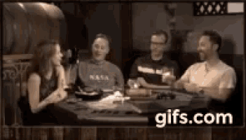 a group of people are sitting around a table with gifs.com written on the bottom