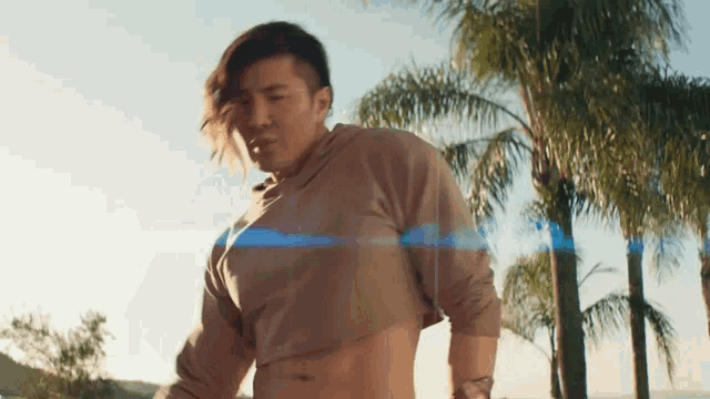 a man wearing a crop top with palm trees in the background