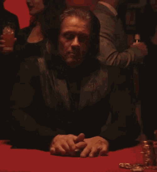a man is sitting at a table with his hands folded in front of him