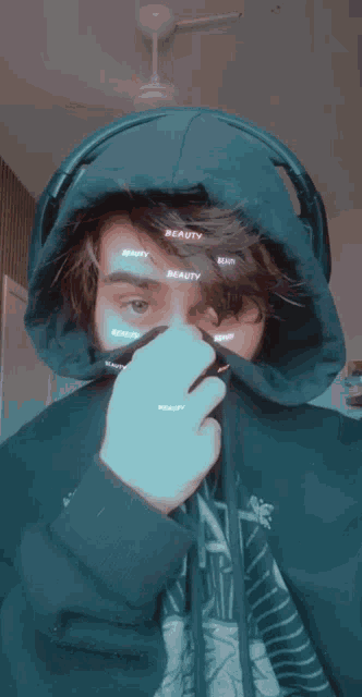 a man wearing a black hoodie with the word beauty written on his face