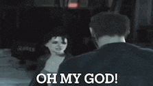 a man and a woman are standing next to each other in a dark room and the woman is saying oh my god .