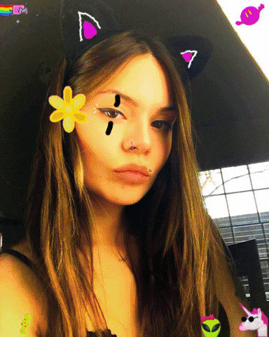 a woman wearing a cat ear headband has a flower on her face and a rainbow in the background