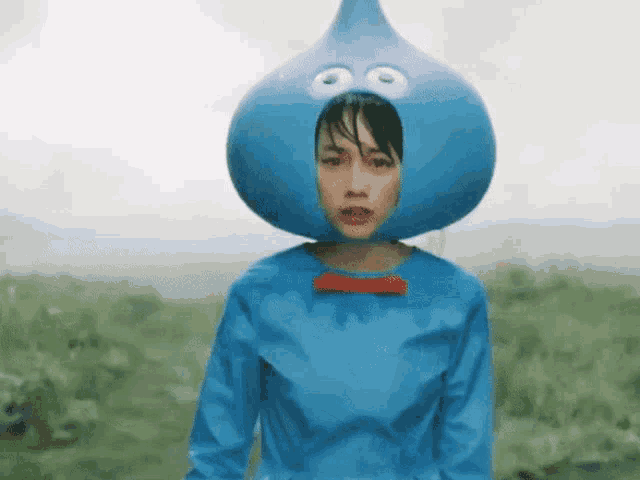 a woman is wearing a blue costume with a big blue teardrop on her head