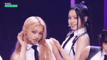 a couple of girls are standing next to each other on a stage and smiling .