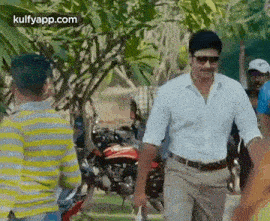 a man in a white shirt and khaki pants is walking down a street .