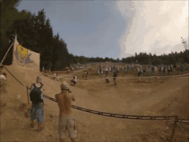 a man taking a picture of a group of people in a dirt field