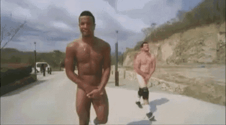 a naked man is walking down a street next to another naked man .