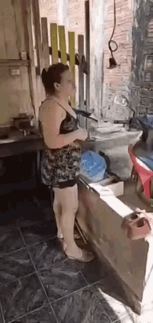 a woman in a short dress is standing in a kitchen .