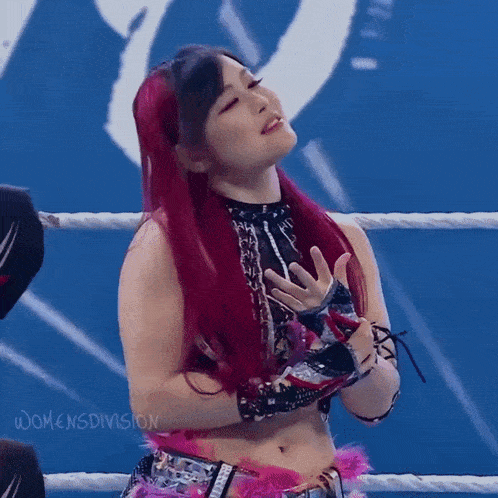 a woman with red hair is standing in a ring with her hands on her chest .