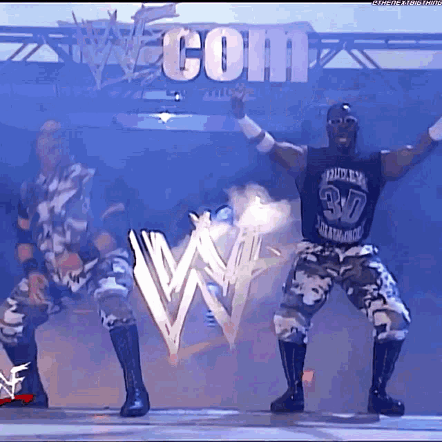 two wrestlers are dancing in front of a w logo