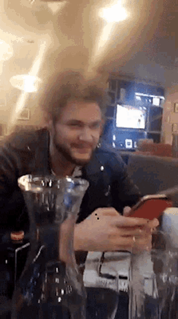 a man is sitting at a table looking at his cell phone