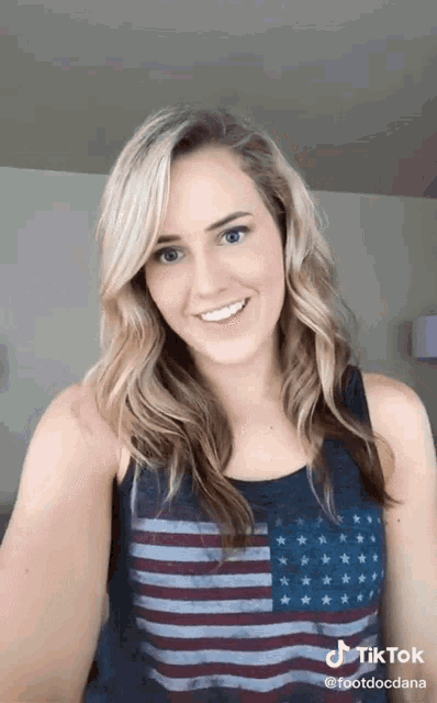 a woman wearing a tank top with an american flag on it is smiling