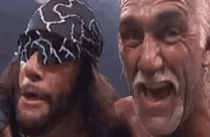 two wrestlers are posing for a picture together and one of them is wearing a bandana .