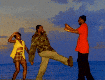 a group of people are dancing on the beach and one of them is wearing a red shirt