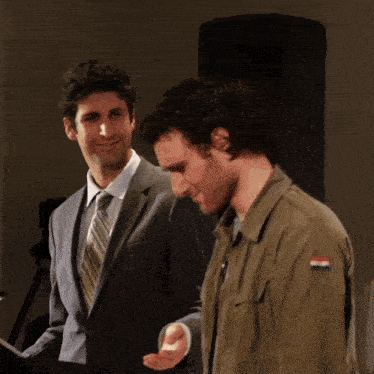 a man in a suit and tie stands next to another man in a military jacket