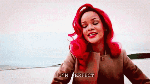 a woman with red hair says i 'm perfect in front of a body of water .