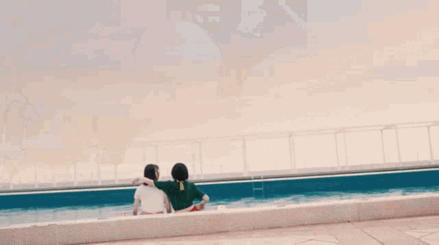 two girls are sitting next to each other on the edge of a fountain