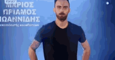 a man with a beard is standing with his hands on his hips in front of a blue background with greek writing .