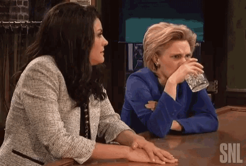 two women sit at a bar with snl written on the bottom right