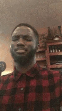 a man with a beard is wearing a plaid shirt and making a face .