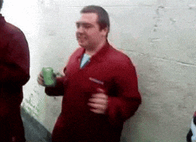 a man in a red jacket holds a green can of soda