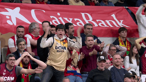 a group of people in a stadium with a banner that says caixabank behind them