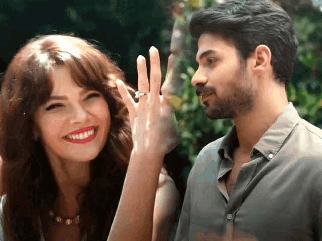 a man and woman are smiling and the woman is wearing a wedding ring
