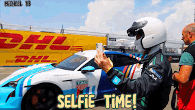a man taking a picture of a race car with the words selfie time below him