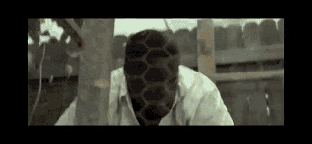 a man with a beehive on his face is standing next to a tree .