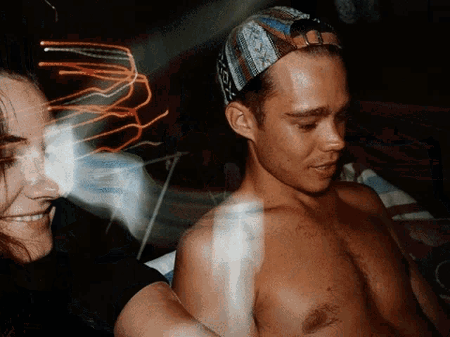 a man without a shirt is wearing a hat that says ' x ' on it