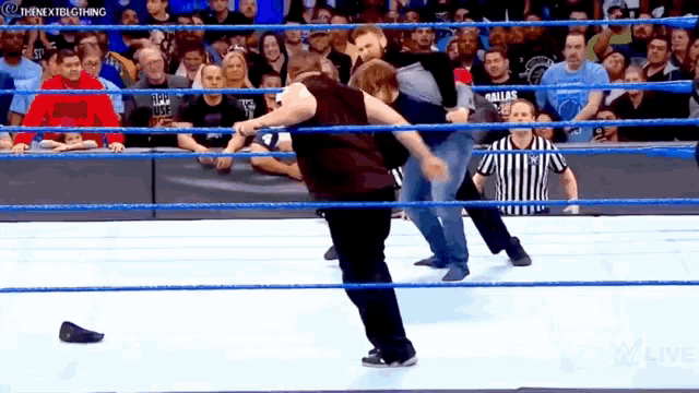 two men are wrestling in a wrestling ring while a referee watches on .