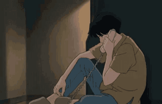 a man is sitting on the floor and talking on a telephone .