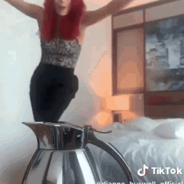 a woman with red hair is jumping over a tea kettle that says tiktok on the bottom