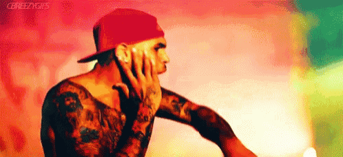 a man with a lot of tattoos is wearing a red hat .