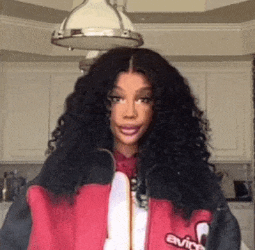 a woman with curly hair is wearing a red and black jacket and a red shirt .