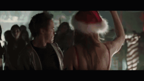 a woman wearing a santa hat is dancing with a man in a crowd .
